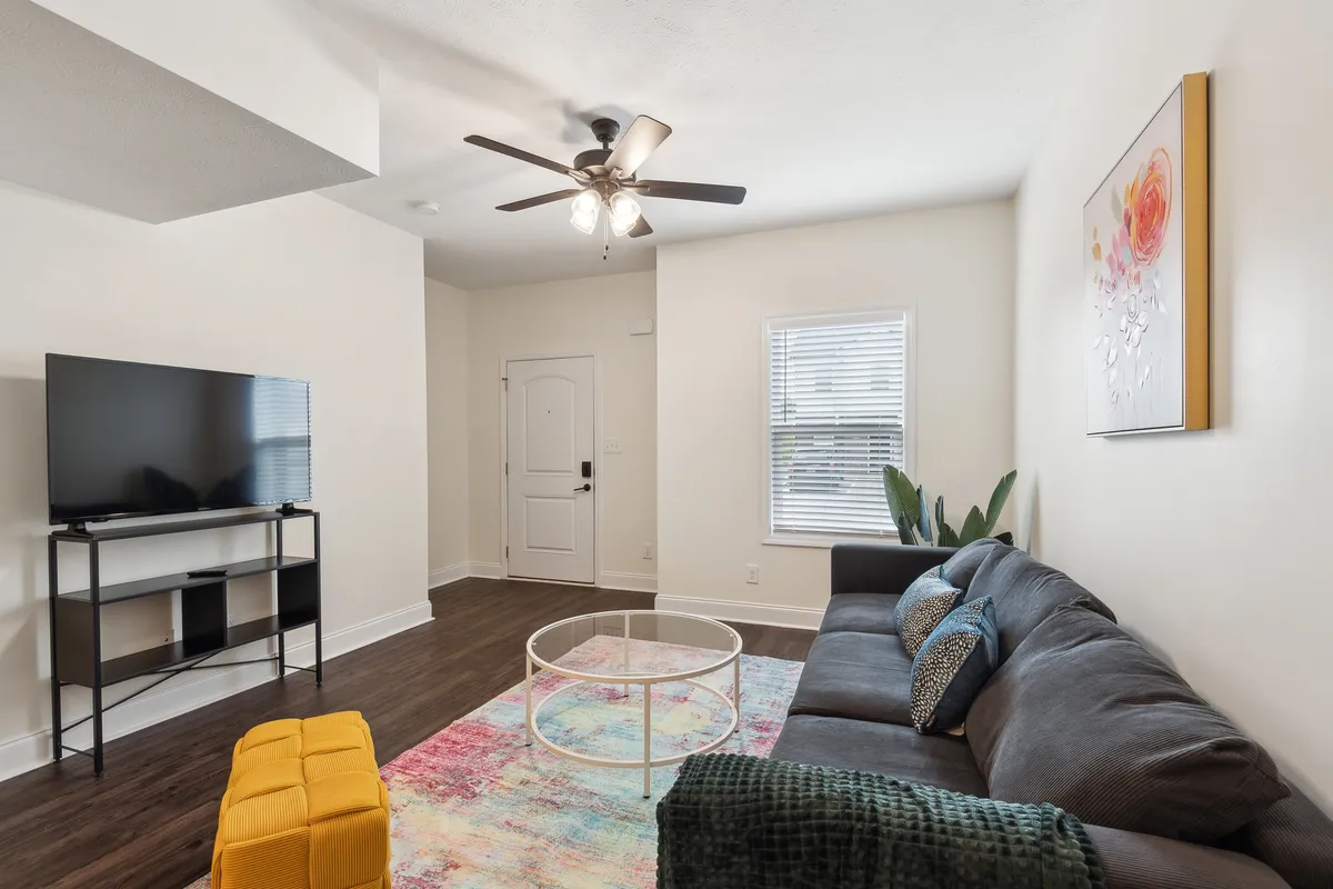 This image captures a comfortable living area featuring a sofa, coffee table, TV, and artwork on the wall. The open layout is inviting, with ample space for guests or family members to gather, relax, or enjoy entertainment together. The decor is modern yet cozy, adding to the sense of comfort.
