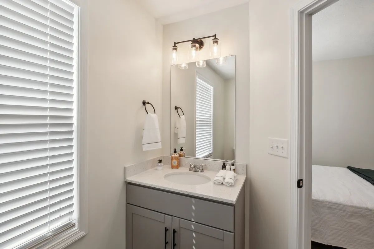 A serene bathroom featuring a contemporary vanity with a sink, a large mirror, soft lighting, and neatly arranged towels and toiletries. The space feels calm and inviting, ideal for daily routines or moments of self-care.