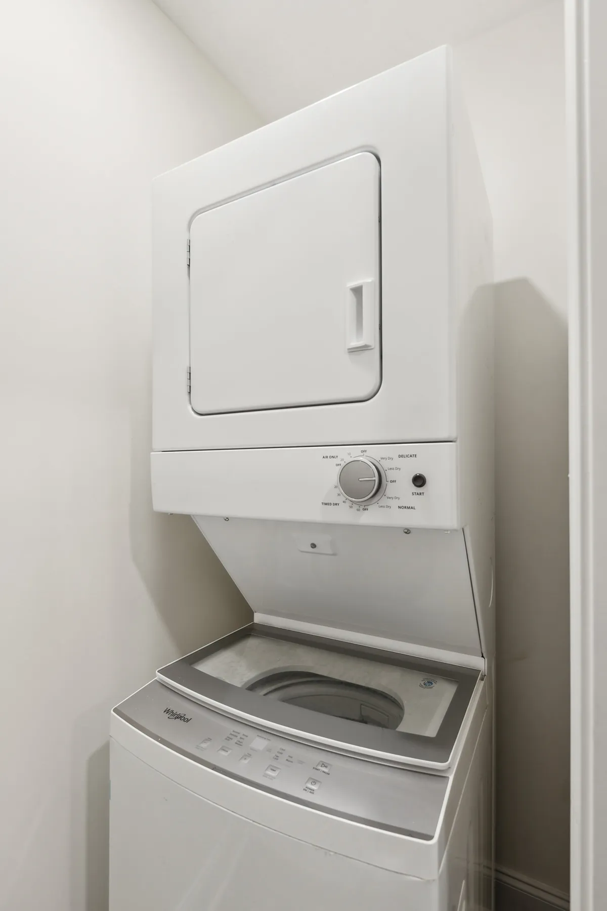 A practical stacked washer and dryer set in a bright, accessible laundry nook. The control panel is easy to reach, and fresh towels are visible, underscoring daily convenience.