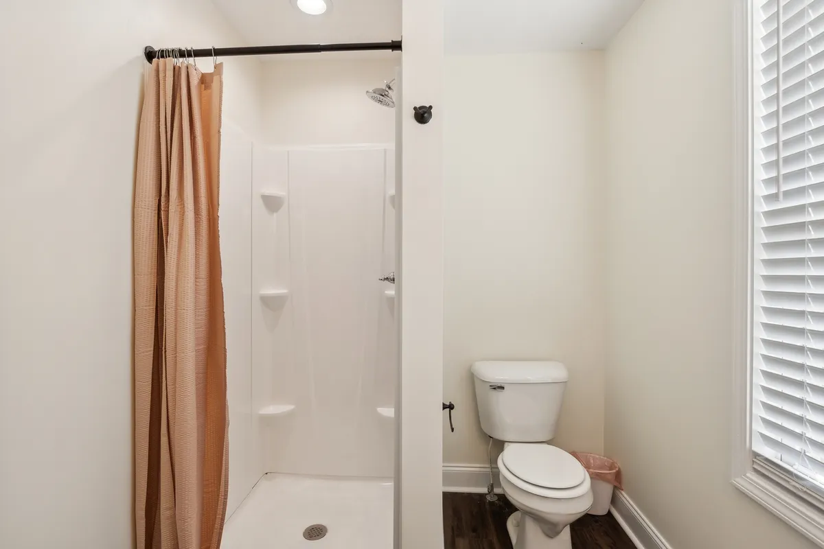 A clean and functional bathroom with a visible shower area, toilet, and shower curtain, designed for easy self-care routines.